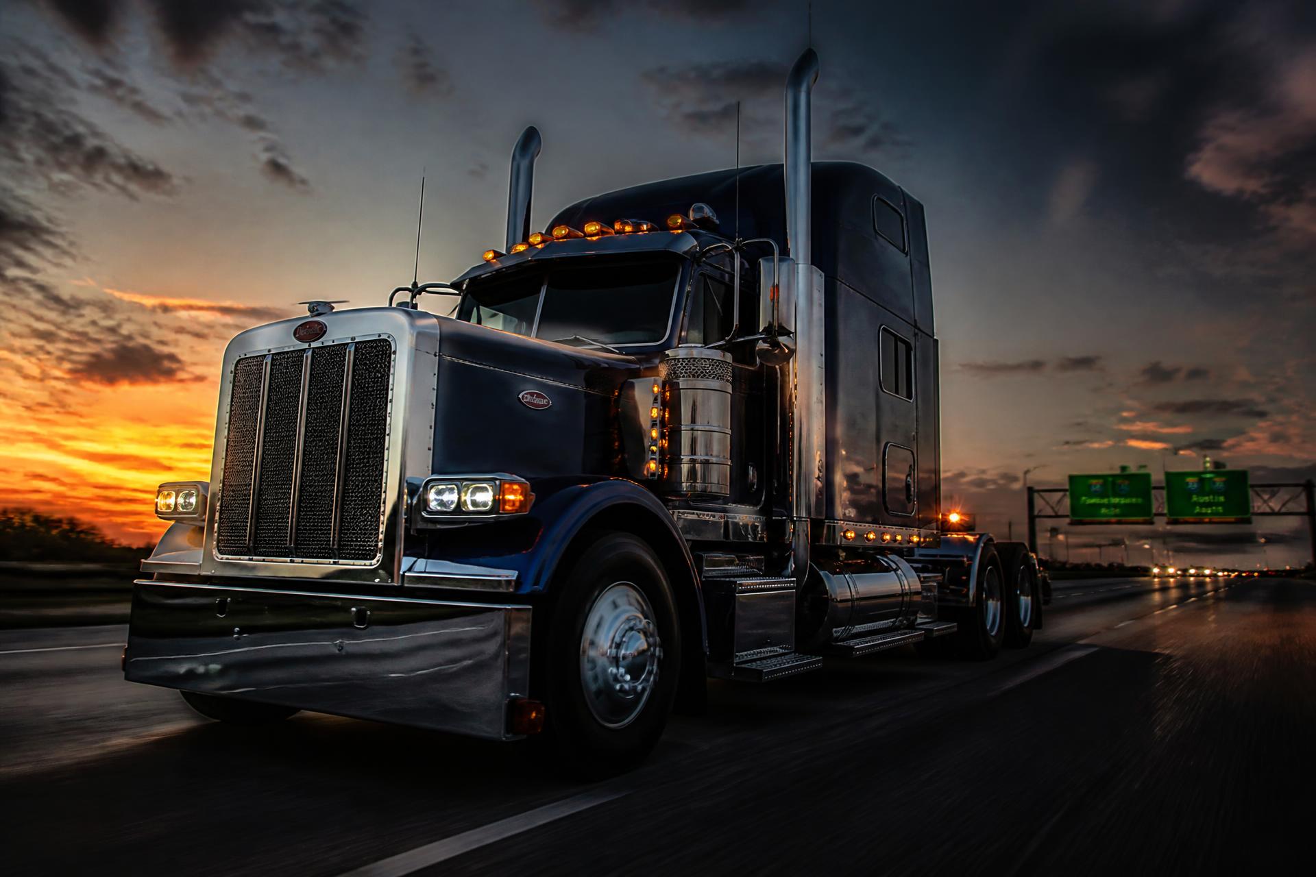 Modern semi truck tractor being transported across the interstate at dusk